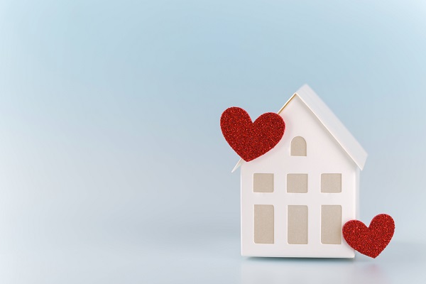White little house with red hearts White little toy house with two red hearts on blue background, family concept copy sp