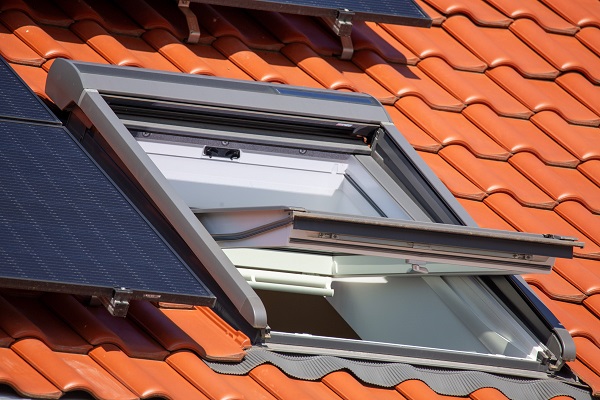 Geöffnetes Dachfenster an einem neuen Ziegeldach mit Solarkollektoren *** Opened skylight on a new tiled roof with solar